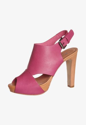 Fuksjowe skórzane sandały na wysokim obcasie z otwartym palcem, krzyżowym designem, regulowanym paskiem przy kostce i jasnobrązową platformą.