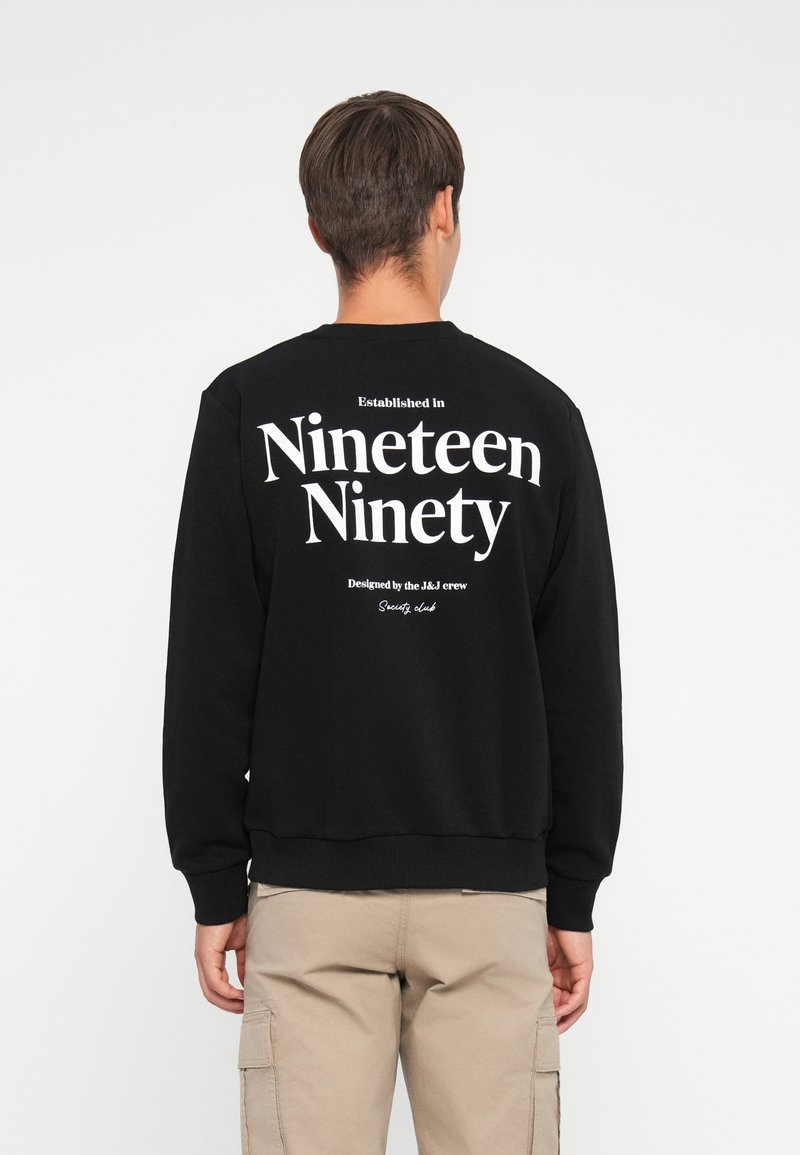 Black sweatshirt featuring large white text on the back: "Established in Nineteen Ninety" and "Designed by the J&J crew." Soft fabric.