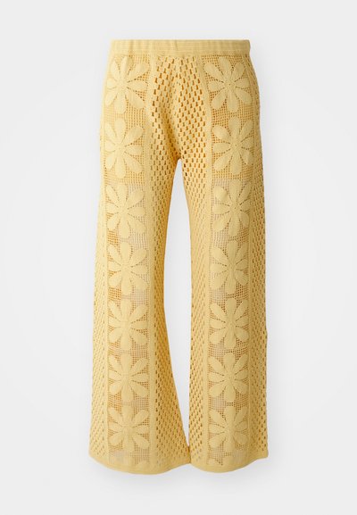 Pantalon en crochet jaune avec un motif floral, coupe large, et une taille élastique avec un design en maille ouverte texturée.