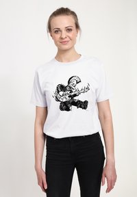 Bílé bavlněné tričko s černou grafickou ilustrací postavy hrající na kytaru s plameny, doplněnou logem a punkovým oblečením.