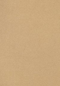 Getextureerde beige stof met een strakke weving, met een subtiel, uniform patroon. Het materiaal lijkt stevig en flexibel.