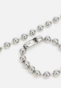Silver beaded necklaces with rounded, polished spheres. One features an oval clasp; both display a smooth, reflective surface.