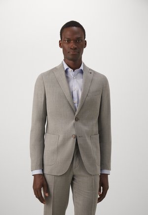 Lys grå skræddersyet jakkesæt med notch lapel, to-knaps lukning og forlommer. Langærmet lyseblå skjorte nedenunder. Glat tekstur.