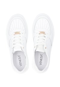Weiße synthetische Sneakers mit durchbrochener Verzierung, flachen Schnürsenkeln und einem metallischen Akzent auf der Zunge. Logo auf der Innensohle sichtbar.