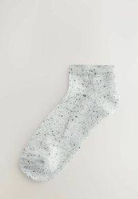 Szürke pettyes zokni, bordás szegéllyel, puha anyagból készült. Klasszikus formával rendelkezik, lekerekített lábujjal és finom textúrával az egész felületen.