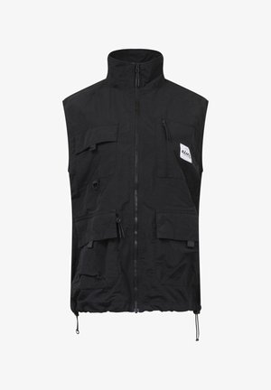 Zwarte mouwloze vest van lichtgewicht stof, met meerdere Franse zakken, een hoge kraag en een verstelbare koord in de zoom.