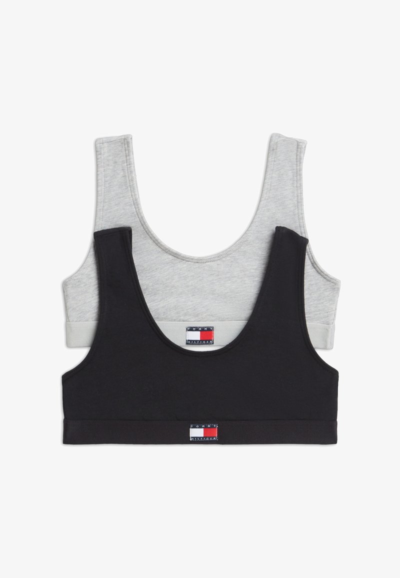 Δύο αθλητικά σουτιέν Tommy Hilfiger, ένα μαύρο και ένα ανοιχτό γκρι, στοιβαγμένα με ετικέτες λογοτύπου στην μπροστινή κεντρική ταινία.