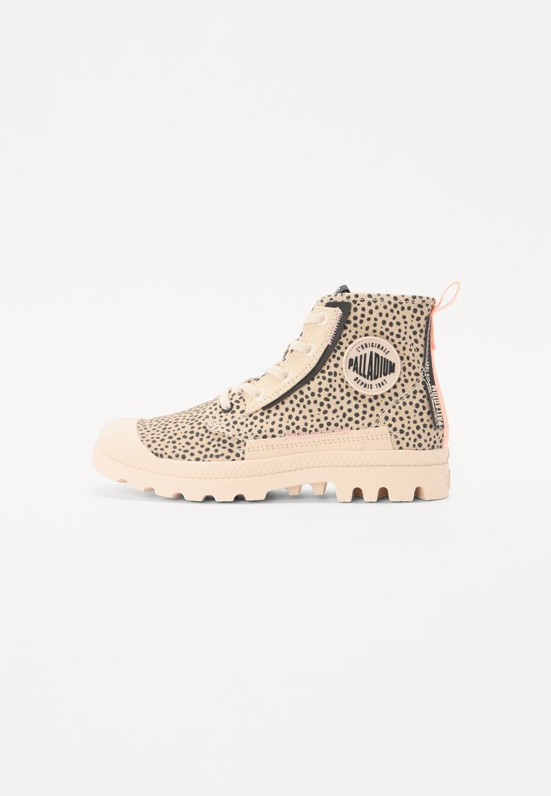 Botas de tobillo beige con patrón de puntos negros, suela de goma y cierre de cordones. Presenta un parche con el logo y una lengüeta en la parte posterior.