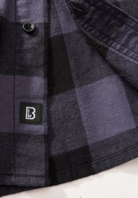 Zwarte en paarse geruite flanellen shirt met een zwarte knoop, textuurstof en een klein merklabel met een wit logo.