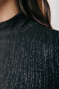 Material texturat negru cu un guler înalt, având dungi verticale argintii care oferă un efect strălucitor. Vedere de aproape a materialului.