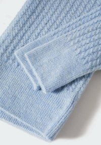 Maglione lavorato a maglia di colore blu chiaro con un motivo testurizzato, dotato di polsini a coste e una sensazione morbida e soffice. Cuciture dettagliate lungo i bordi.