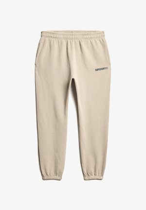 Beige katoenen joggingbroek met elastische tailleband en boorden, uitgerust met zijzakken en het "SUPERDRY"-logo in het blauw op het bovenste deel van het rechterbeen.