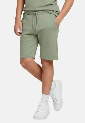 Lichtgroene katoenen shorts met een elastische tailleband en trekkoord, voorzien van zijzakken en een casual, knielange pasvorm. Gecombineerd met witte sneakers.