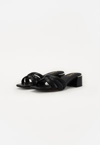 Schwarze Riemchensandalen mit Blockabsatz, ausgestattet mit gewebten Riemen über dem Obermaterial und einer glatten Textur auf der Innensohle.