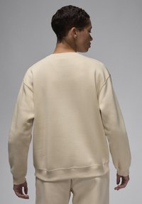 Felpa beige realizzata in tessuto morbido con una vestibilità ampia. Presenta polsini e orlo a costine, e un design semplice e senza decorazioni sul retro.