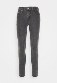 Jeans skinny de mezclilla negra con cinco bolsillos, cierre de botón y cremallera, trabillas para el cinturón y un acabado ligeramente desgastado en toda la prenda.