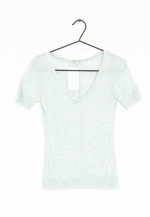 Jasnozielona, krótka bluzka z krótkim rękawem i dekoltem w serek, wykonana z miękkiej, teksturowanej tkaniny. Posiada metkę na linii szyi i wisi na czarnym haczyku.