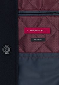 Navy wełniany płaszcz z burgundową pikowaną podszewką, o błyszczącej teksturze, z metkami "extra fine WOOL" i "Made in Europe", oraz czarnym guzikiem.
