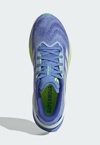 Blue athletic shoe with textured mesh upper, green accents, flat laces, and cushioned sole; features logo on tongue and two stripes on side.