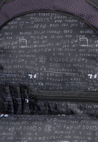 Un interno nero con motivi geometrici bianchi, inclusi forme, linee e cerchi; presenta numerose tasche e una chiusura con zip.