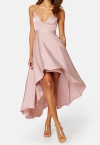 Robe rose clair à ourlet asymétrique en tissu satin, avec un décolleté plongeant, des bretelles ajustables et un ourlet fluide à plusieurs couches.