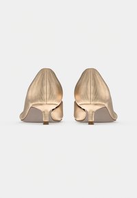 Παπούτσια σε χρυσό χρώμα με υφή, μύτη που στενεύει και μικρό τακούνι. Ο σχεδιασμός περιλαμβάνει λείο πίσω μέρος με κομψό άνοιγμα.