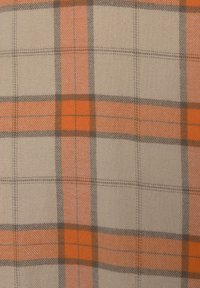 Kariertes Gewebe mit einem beigen Hintergrund und orangefarbenen sowie grauen Linien, die Quadrate bilden. Die Textur wirkt weich und gewebt.