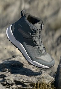 Grau Wanderschuh mit einer strukturierten Oberseite, GORE-TEX-Branding und einer weißen Sohle. Er verfügt über Schnürsenkel und einen gepolsterten Kragen für Stabilität.