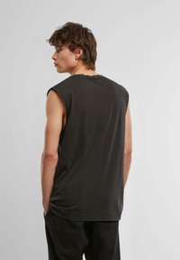 Sleeveless dark gray cotton t-shirt with a relaxed fit and low armholes, featuring a subtle rounded neckline and a soft texture.