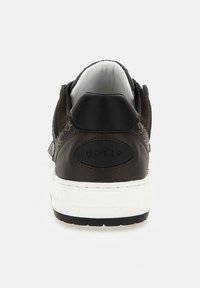 Sneaker marrone con una parte superiore testurizzata, suola bianca e una patch nera con il logo sul tallone. Presenta accenti di cucitura e un colletto imbottito.