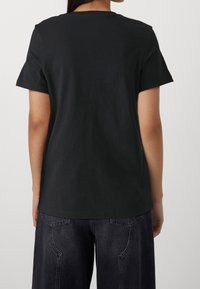 Sort bomulds t-shirt med korte ærmer og rund halsudskæring, vist fra bagsiden; har en glat tekstur og en afslappet pasform.