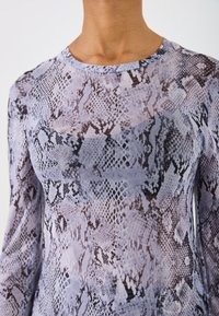 Top cu mânecă lungă dintr-un material translucent, cu un model de imprimeu cu șarpe în nuanțe de violet și negru. Are un guler rotund și o siluetă ajustată.