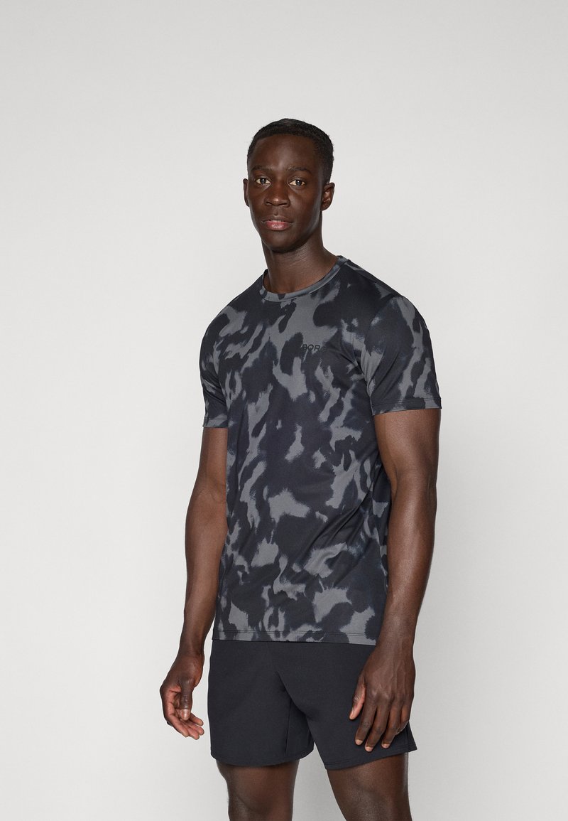 T-shirt de sport à manches courtes en noir avec un motif camouflage gris, fabriqué en tissu léger, doté d'un col rond et d'une coupe ajustée.