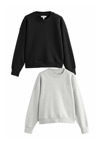 Twee crewneck sweaters, één zwart en één lichtgrijs. Beide hebben brede schouders, ribbelmanchetten en een relaxte pasvorm. Zachte textuur.