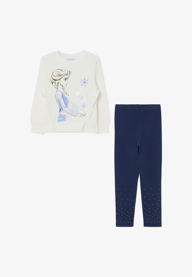 Witte sweatshirt met een grafisch ontwerp van een karakter en blauwe sneeuwvlokken, gecombineerd met marineblauwe legging die zilveren studs aan de zoom heeft.