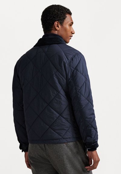 Jūras spēku kvadrātmetru jaka ar kordūra apkakli, kurai ir teksturēta virsma un elastīgas aproces, redzama no aizmugures.