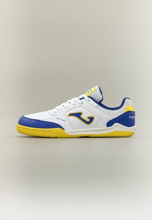 Bela športna obutev z modrimi in rumenimi poudarki, rumeno podplatom in modrim logotipom na strani, zasnovana za notranje aktivnosti.