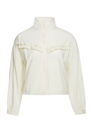 Giacca corta color avorio con zip frontale, collo alto, polsini elastici lunghi e dettaglio di balza orizzontale sul petto.