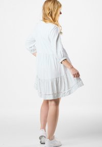 Hellblau gestre dresses mit Dreiviertelärmeln, gestuftem Rock und Spitzenverzierungen. Getragen mit weißen Sneakers.