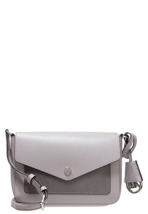Petit sac bandoulière gris clair avec finition texturée, fermeture à rabat, sangle réglable et breloque ronde en métal avec logo sur le côté.
