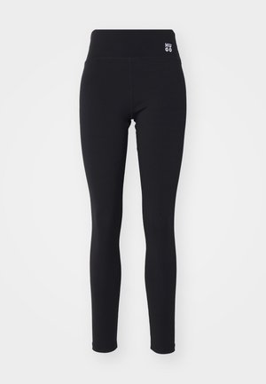 Schwarze Leggings aus dehnbarem Stoff mit einem hohen Bund und einem kleinen weißen Logo "HUGO" an der Seite. Glatte Textur, enganliegendes Design.