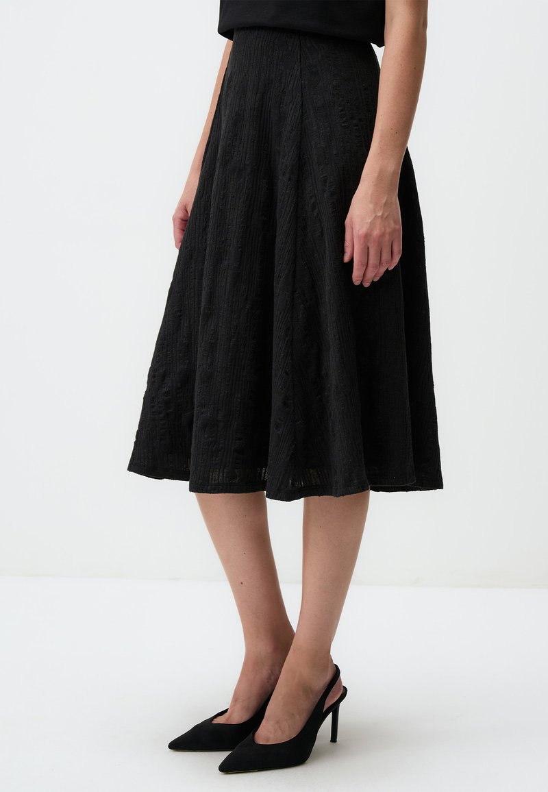 Gonna midi nera con tessuto testurizzato, design svasato e vita liscia. Abbinata a scarpe con tacco a punta nere.