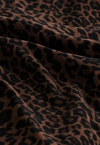Brauner Stoff mit einem Leopardenmuster. Das Muster zeigt große schwarze Flecken mit einer strukturierten Oberfläche, die einen reichen visuellen Kontrast erzeugt.