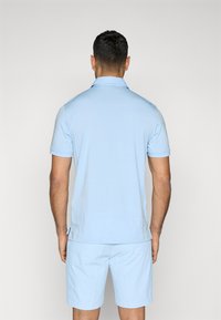 Light blue polo shirt with short sleeves, flat collar, and a straight hem, paired with matching light blue shorts. Minimalistic design.