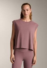 Top liliac fără mâneci, cropt, dintr-un material moale, cu decolteu rotund. Prezintă o croială lejeră și o margine netedă, asortat cu colanți în aceeași nuanță.