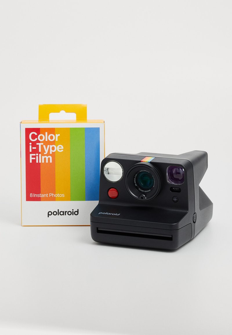 Melnbalts Polaroid instant fotoaparāts ar varavīksnes akcentiem, sarkanu pogu un apaļu objektīvu. Iekļauta Color i-Type filma 8 fotogrāfijām.