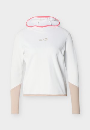 Camisa blanca de manga larga con capucha, con mangas inferiores y dobladillo en beige, ribete rosa dentro de la capucha y pequeño logo dorado de infinito en el pecho.