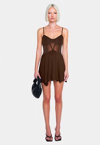 Abito marrone con corpetto aderente e pannelli trasparenti, gonna fluente, spalline sottili e orlo a strati. Accompagnato da una borsa nera con texture.