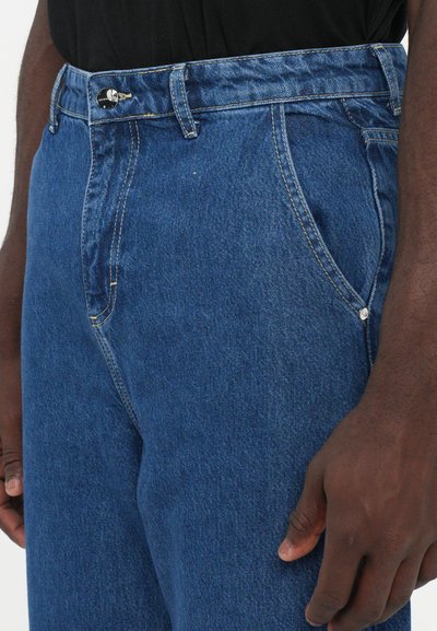 Τζιν παντελόνι σε σκούρο μπλε χρώμα με ίσια γραμμή, διαθέτει κουμπί στο μπροστινό μέρος, θηλιές ζώνης και κανονικές τσέπες. Λείος υφασμάτινος ιστός με αντίθετες ραφές.