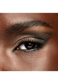 Nahaufnahme eines dunkelbraunen Auges mit definierten Wimpern, subtiler Lidschatten und einer glatten, strukturierten Haut um das Auge.